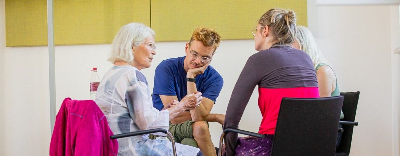 vier Personen sitzen im kreis und sprechen. 