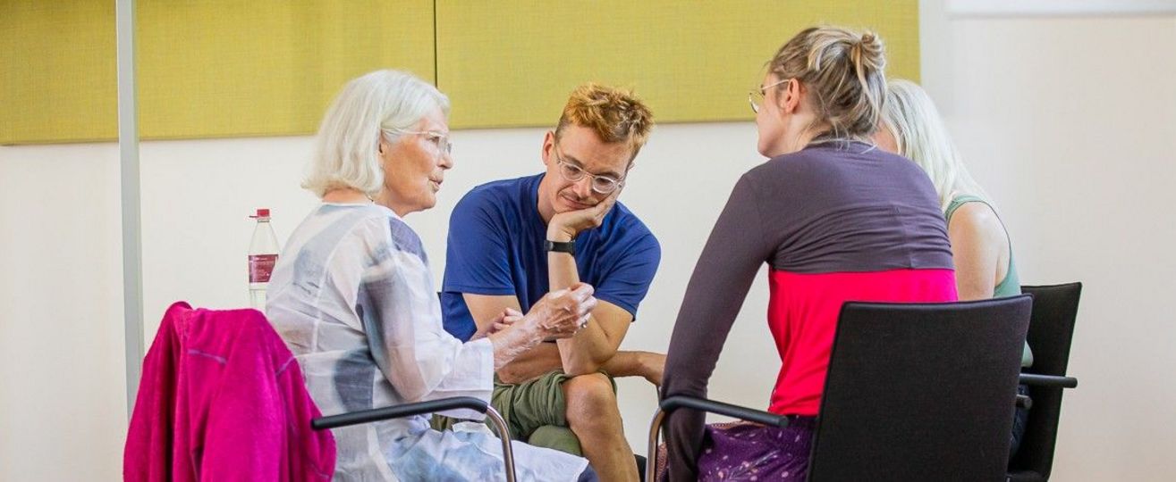 vier Personen im Stuhlkreis diskutieren