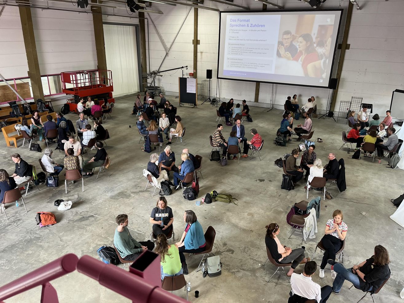 Ein Saal von oben, viele Kleingruppen sind im Gespräch.