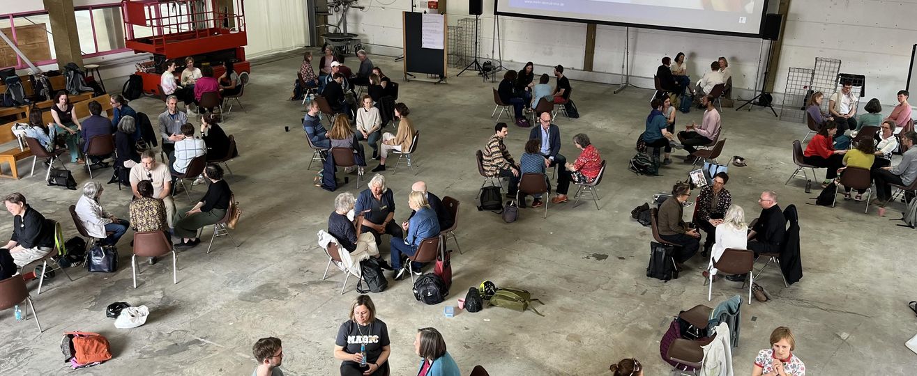 Mehrere Kleingruppen in einem großen Saal, von oben fotografiert